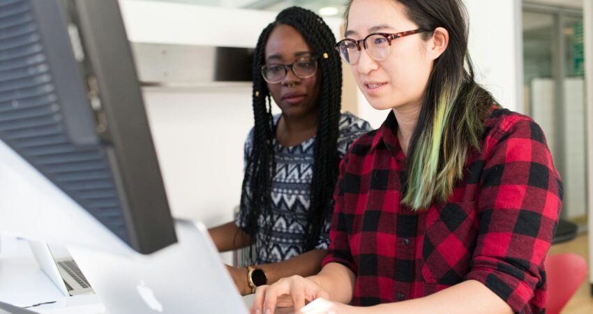 woman wearing red and black checkered blouse using macbook