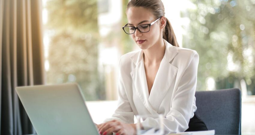 concentrated female entrepreneur typing on laptop in workplace