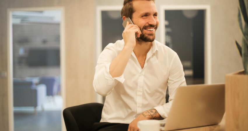 smiling formal male with laptop chatting via phone