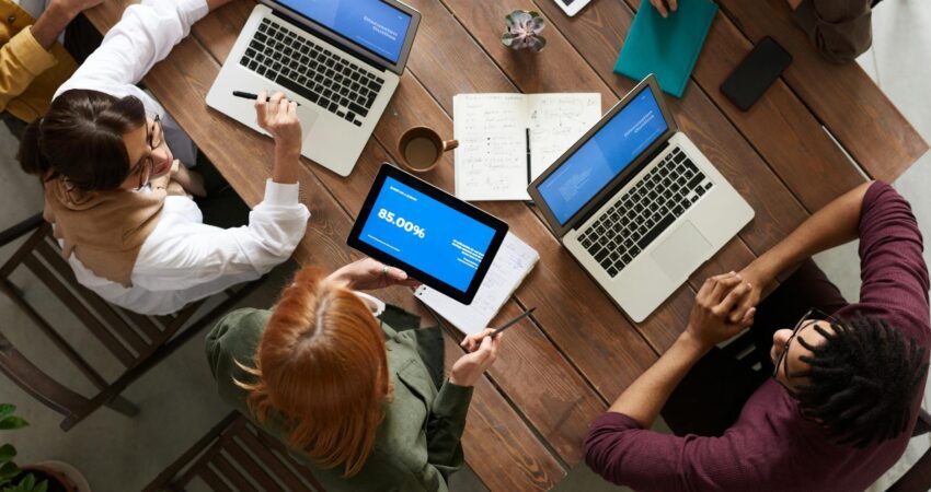 top view photo of group of people using macbook while discussing