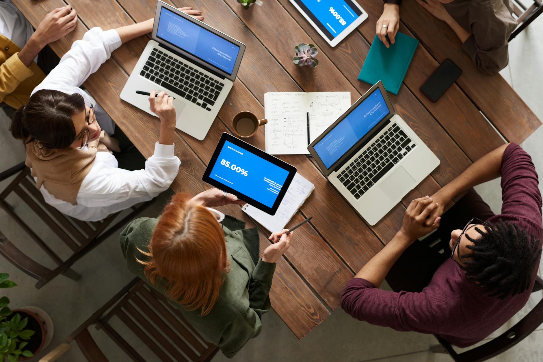 top view photo of group of people using macbook while discussing