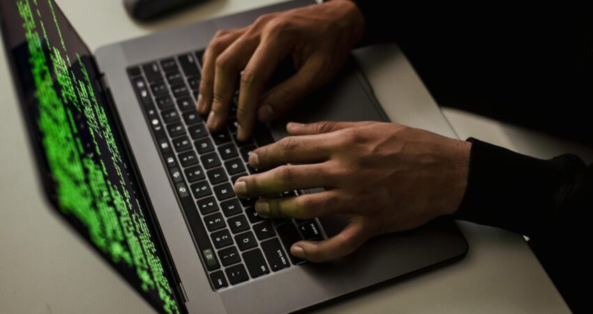 crop cyber spy hacking system while typing on laptop