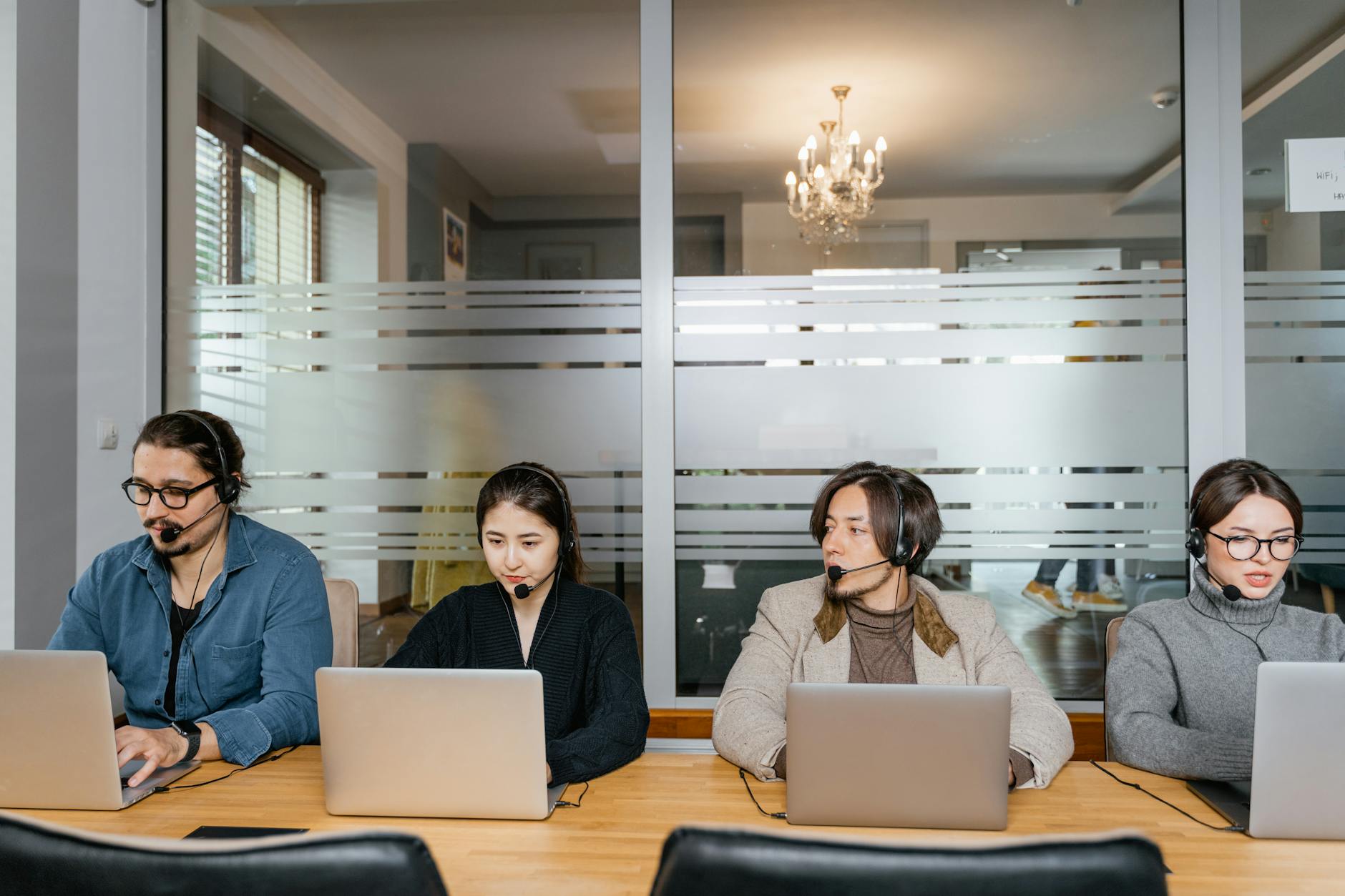 multiracial employees sitting in front of silver laptops