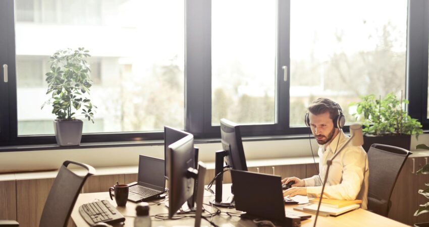 man with headphones facing computer monitor