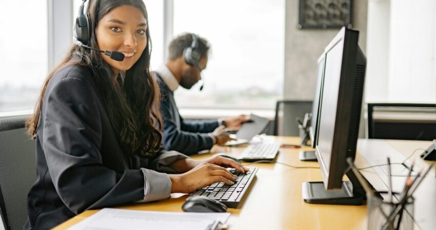 a smiling woman working in a call center while looking at camera