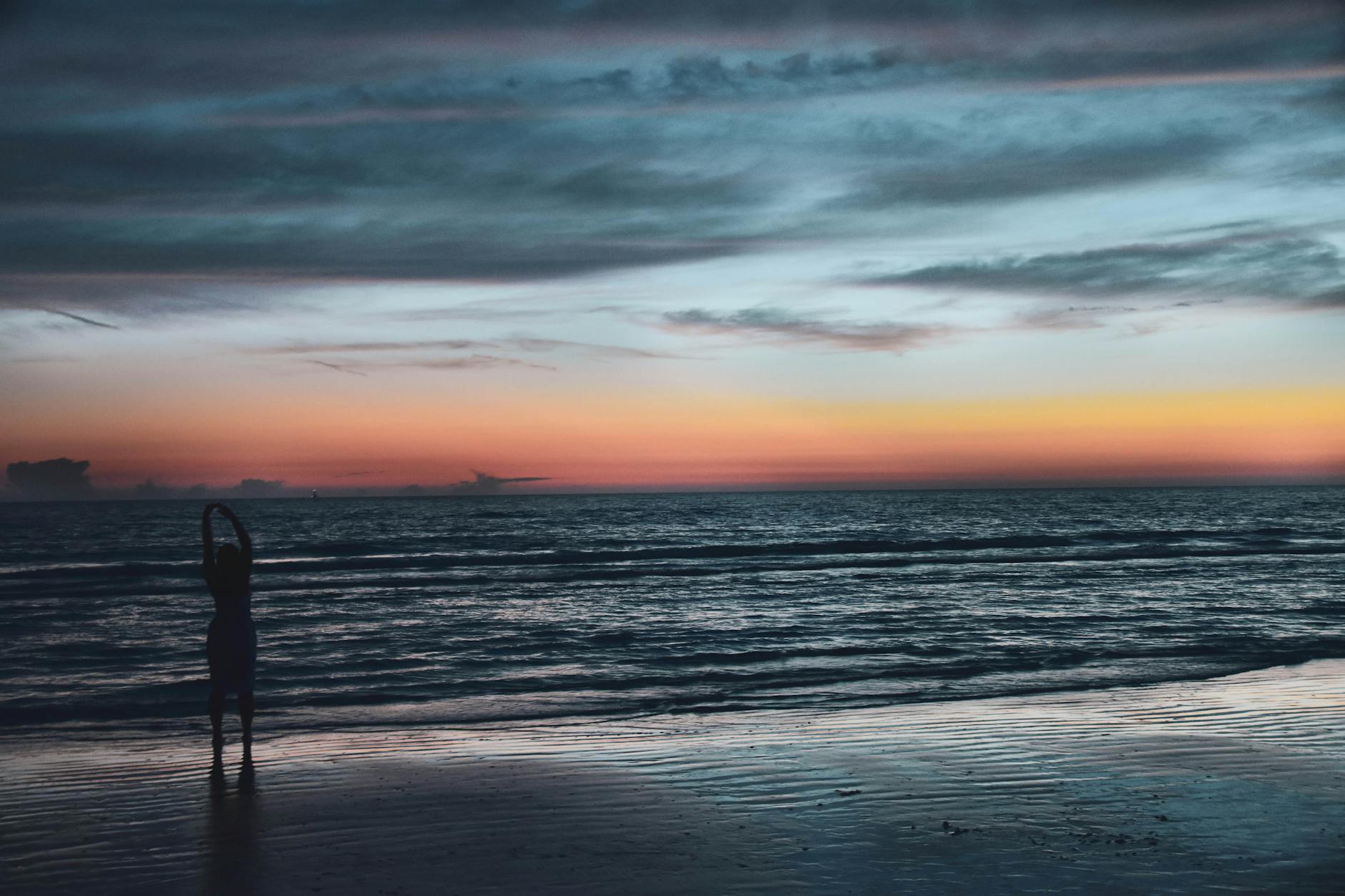 silhouette of person on seashore during golden hour