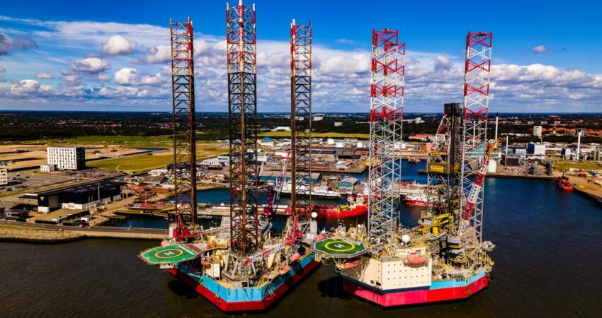 aerial panorama of oil rigs with helipads moored at a port terminal