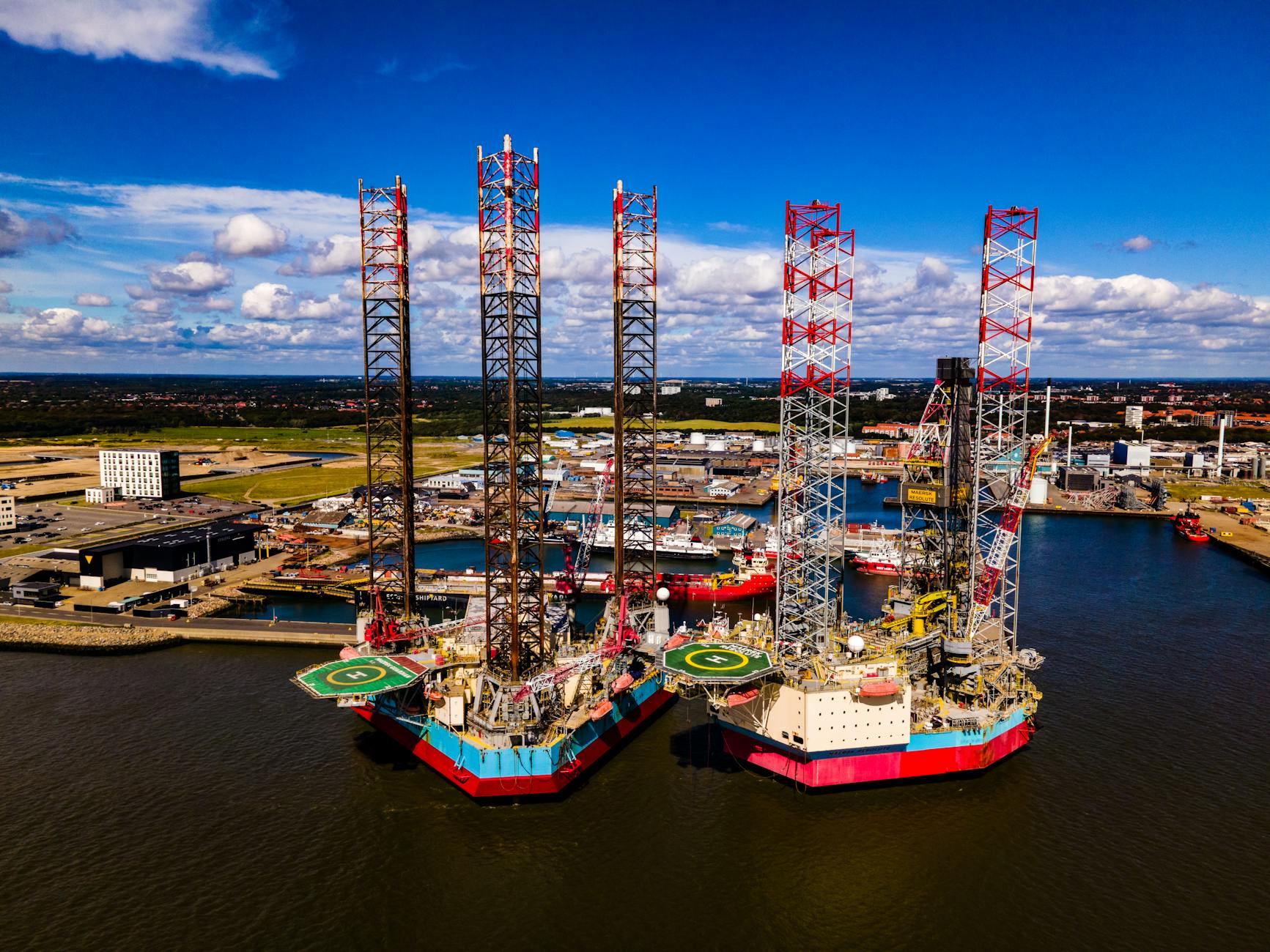 aerial panorama of oil rigs with helipads moored at a port terminal